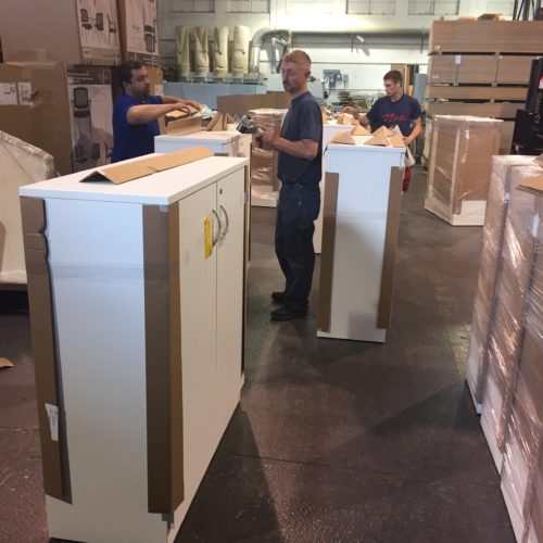 Three men preparing three white cabinets