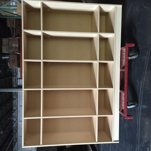 A wooden shelf on wheels in a warehouse.